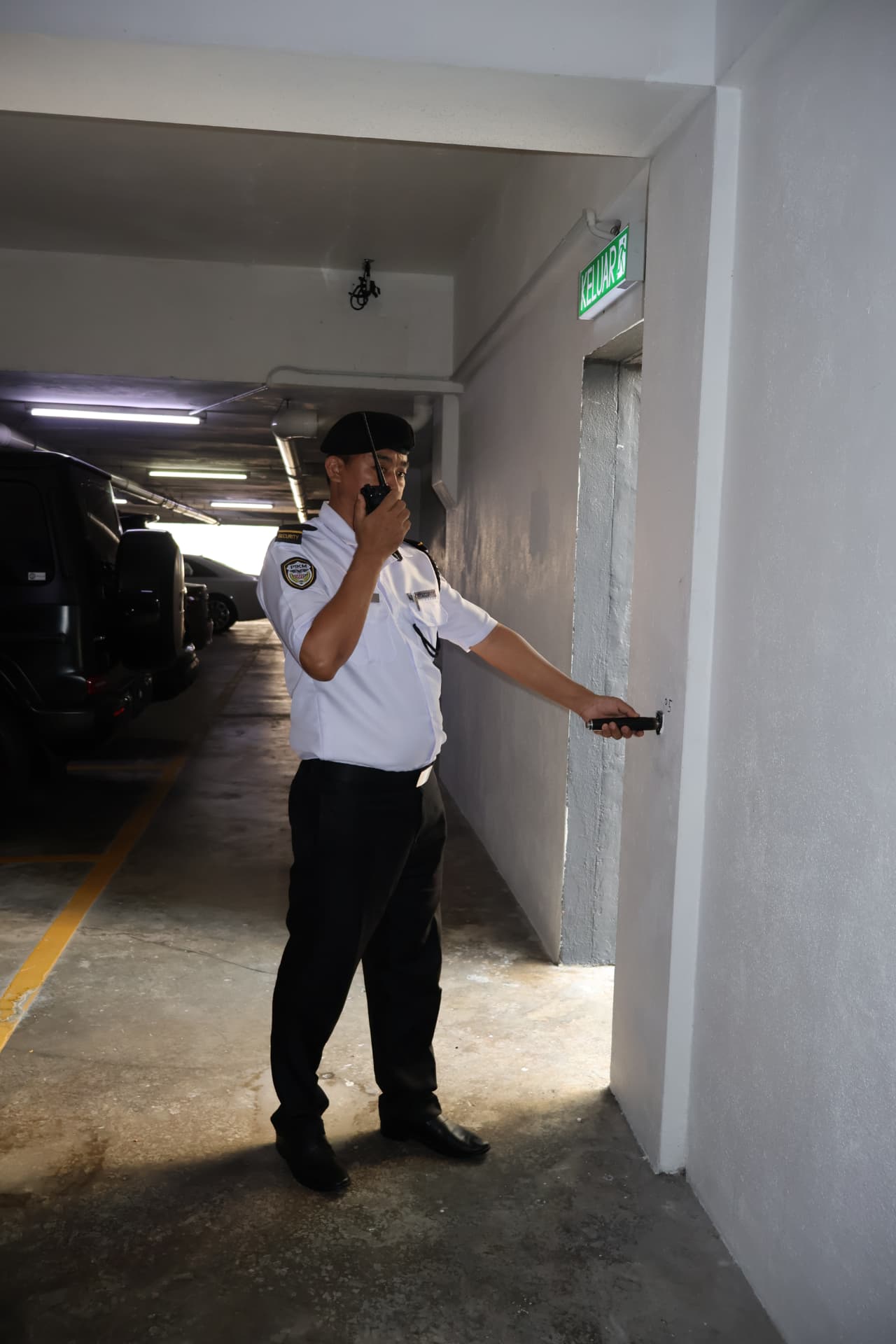 Security officer patrolling a car park with a radio and torch