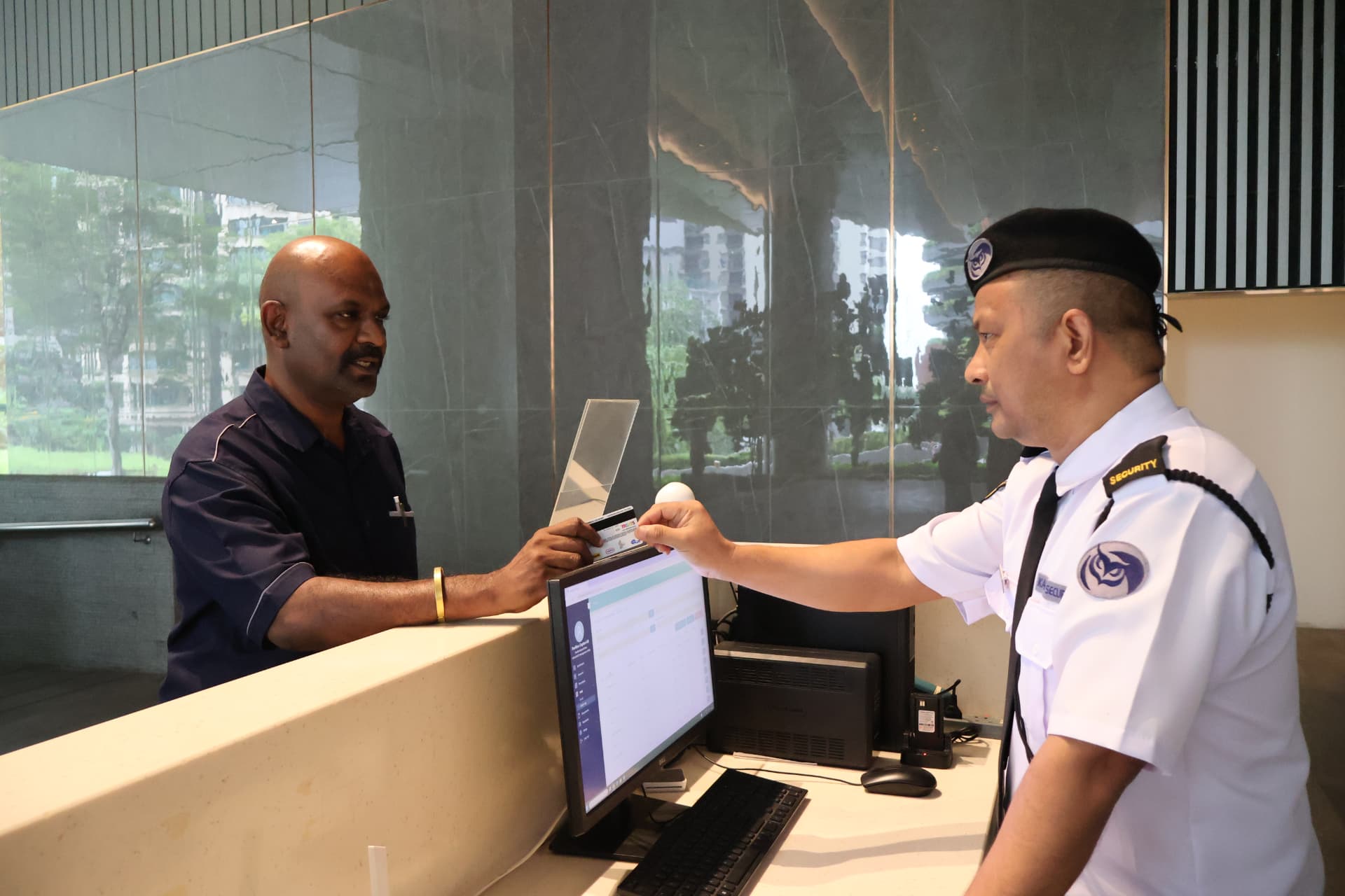 Kaliber security officer handling visitor registration at a building reception counter