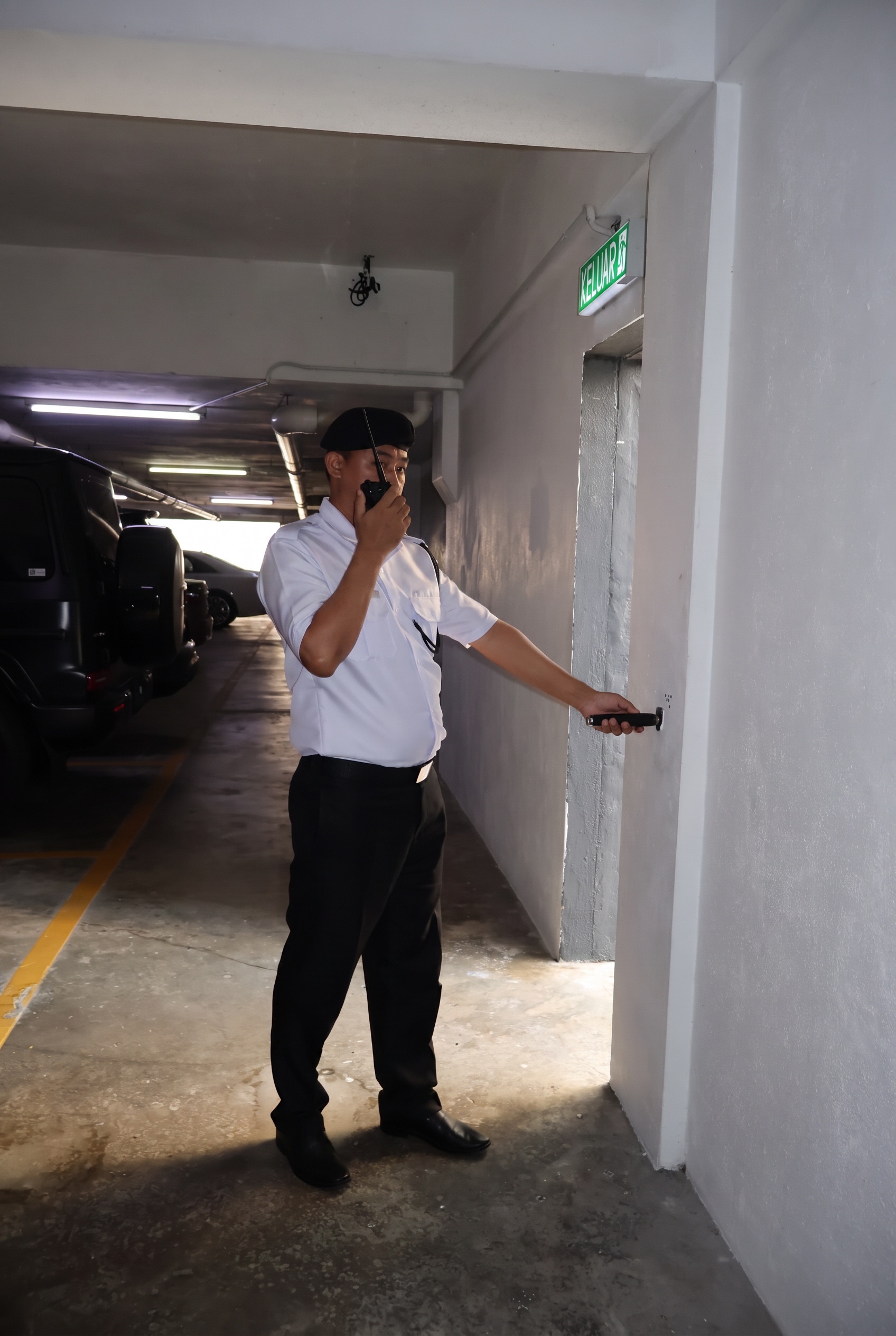 Security officer patrolling a car park with a radio and torch